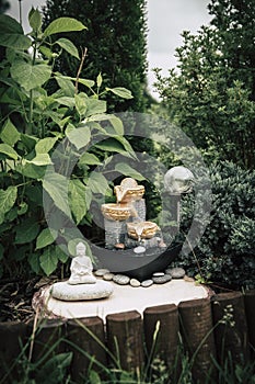 Small home garden private fountain with meditating Buddha statue between trees and bushes.