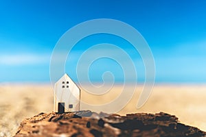 Small home model on sunset beach sand texture background