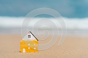 Small home model on sunset beach sand texture background