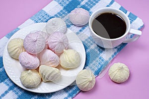 Small homemade meringue kisses. Meringue cookies and coffee cup on blue tablecloth pink background