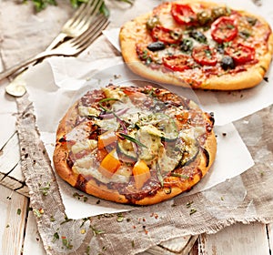 Small homemade vegetable pizzas on a white wooden table