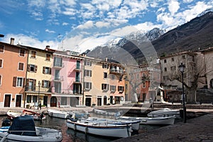 Small hotels in a mountain resort. In the foreground is a pier with pleasure boats