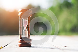 Small hourglass show time is flowing on sand beach background