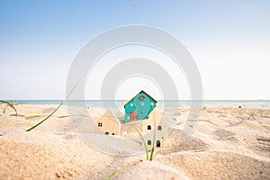 Small house on the beach, building model, wave and sea background, real estate business ideas