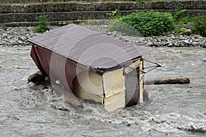 A small house destroyed the mudflow in the mountains. A small house was washed away by a flooded mountain river