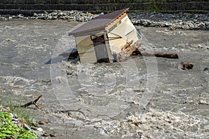 A small house destroyed the mudflow in the mountains. A small house was washed away by a flooded mountain river