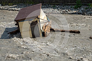 A small house destroyed the mudflow in the mountains. A small house was washed away by a flooded mountain river