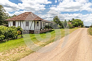 Small house in enxaimel style, dirty road with flowers and plants around photo