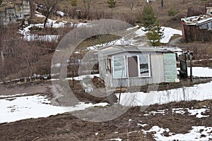 A small house on a garden plot on a hillside, spring, the snow is melting, Moscow region 2021