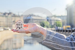 Small house on hand against the background of the city, real estate agent concept, developers, preferential mortgages