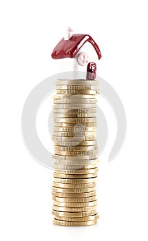 Small house model lifted by a stack of euro coins on white background