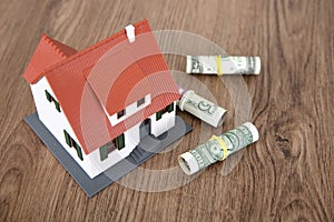 Small house model and scattered dollar bills on the table