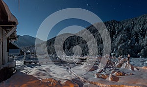 Small house on a winter night with glowing windows in camping in mountains. Small village in Caucasus mountains. Christmas