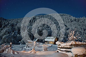 Small house on a winter night with glowing windows in camping in mountains. Small village in Caucasus mountains. Christmas