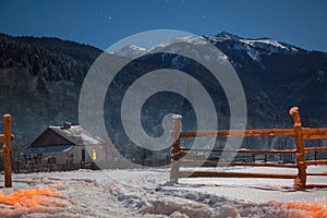 Small house on a winter night with glowing windows in camping in mountains. Small village in Caucasus mountains. Christmas