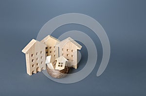 Small houses in a birds nest are surrounded by large buildings. Residential buildings and houses in a bird`s nest. Parenting