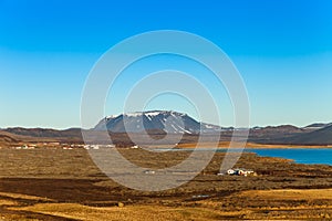 Small houses on the coast of lake on stony rocky deserted landscape of Iceland