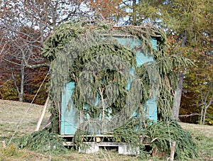 small hunting lodge of hunters camouflaged with green leaves to