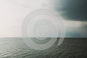 Small hut in the middle of the sea under coming storm.