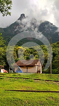 Small hut with a mountain in the background, some clouds on top of the mountain