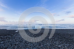 Small ice on black rock sand beach seacoast skyline