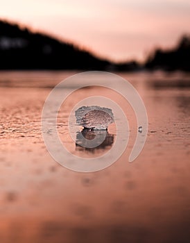 A small ice block is orange on a frozen lake