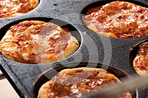 Small individual pizzas in a baking tray