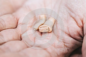 Small intra channel hearing aid device in a man`s hand.