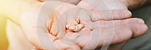 Small intra channel hearing aid device in a man`s hands. banner. flare.