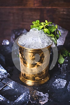 A small iron bucket stands on a table with ice.