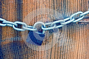 Small iron lock and white chain on a brown board