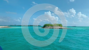 Small island on azure ocean surface against blue cloudy sky