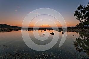 Small island with beautiful light sunset or sunrise over sea and beautiful reflexion in the water