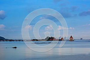 Small island and building with smooth blue sea and reflection of sky like mirror, coast line of Sriracha Thailand