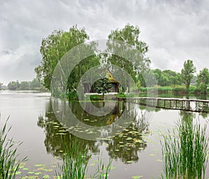 Small island with hut on lake and footbridge during rain photo