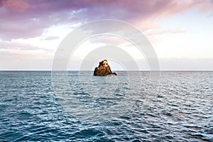 Small island or islet, a small rock cliff surrounded by the blue water from the Atlantic Ocean in Funchal, Madeira, Portugal.