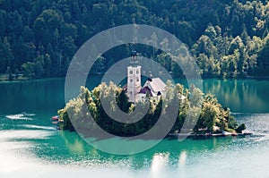 An island with a church with a tall tower in the middle of Lake Bled in Slovenia.