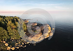 Small island and man with boat, launching drone. Beautiful rocks and cliffs with woods in North Europe, Baltic sea, gulf of