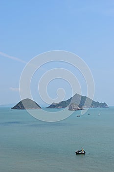 Small island in the sea with blue sky and fluffy cloud in background