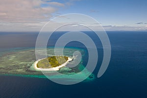 A small island surrounded by azure water and coral reefs, a top view.