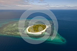 A small island surrounded by azure water and coral reefs, a top view