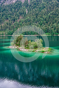 Small islands with pine-trees in the middle of Eibsee lake with Zugspitze mountain. Beautiful landscape scenery with paradise