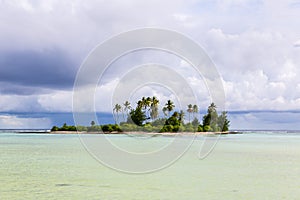 A small islet motu overgrown with palm forest somewhere in the lagoon of Tarawa atoll in bad cloudy weather, Kiribati, Oceania.