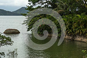 Small isolated stone at the end of a river entering the sea in Paraty, Brazil