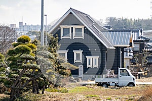 Small Japanese kei truck in front of large country home