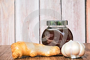 Small jar of honey and, garlic,    ginger  on wooden background