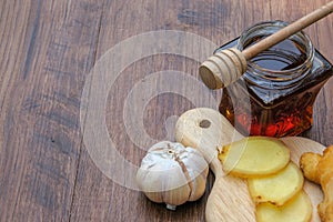 Small jar of honey and, garlic,    ginger  on wooden background