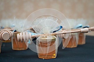 Small jars filled with honey and wrapped in tulle with a honey dipper on it