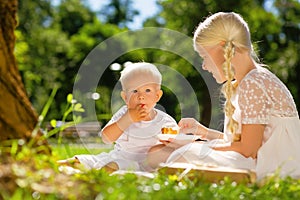 Small kid eating a cake together with a sister