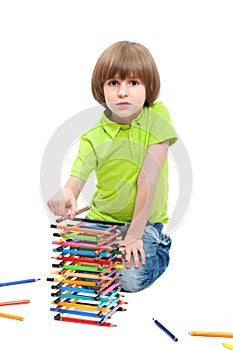 The small kid has built a tower of pencils